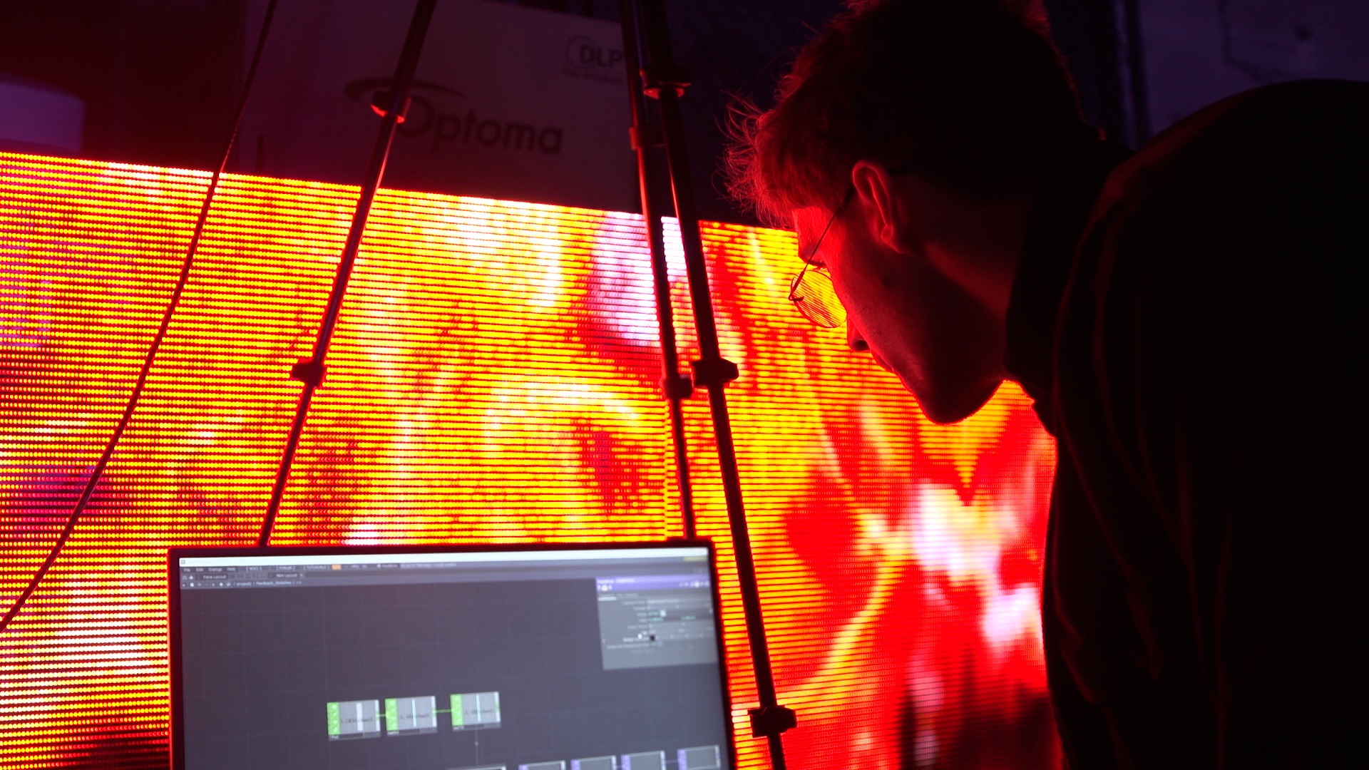 John Syzonenko in profile, working at a laptop in front of an LED wall
